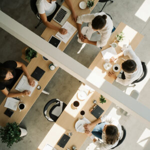 Team collaborating around shared tables in a bright modern workspace.