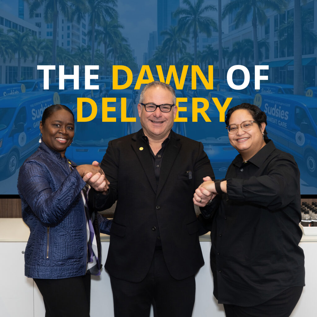 Three Sudsies team members fist-bumping in front of a screen that reads “The Dawn of Delivery”