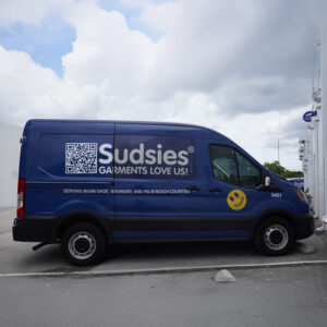 Blue Sudsies delivery van parked outside the facility with branding and service area details