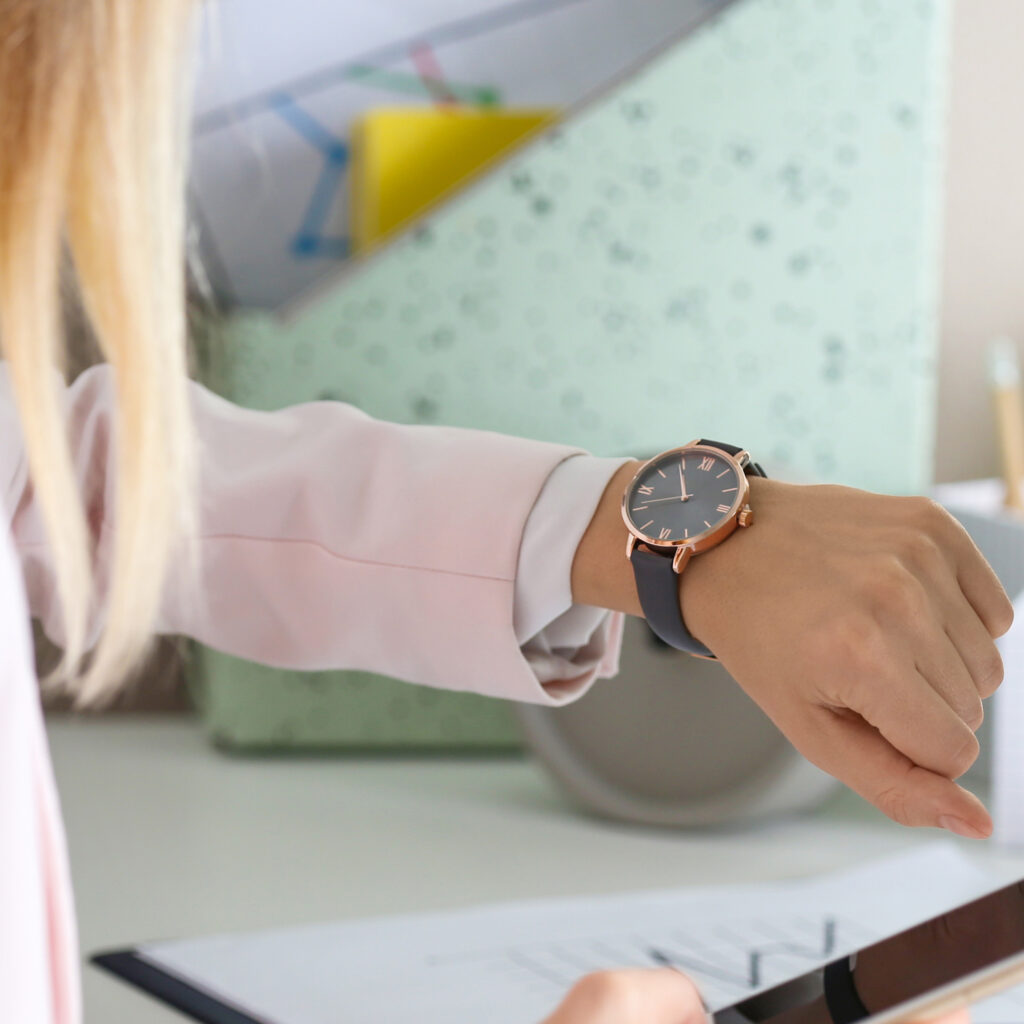 Close-up of a person checking the time on a stylish wristwatch while working at a desk.