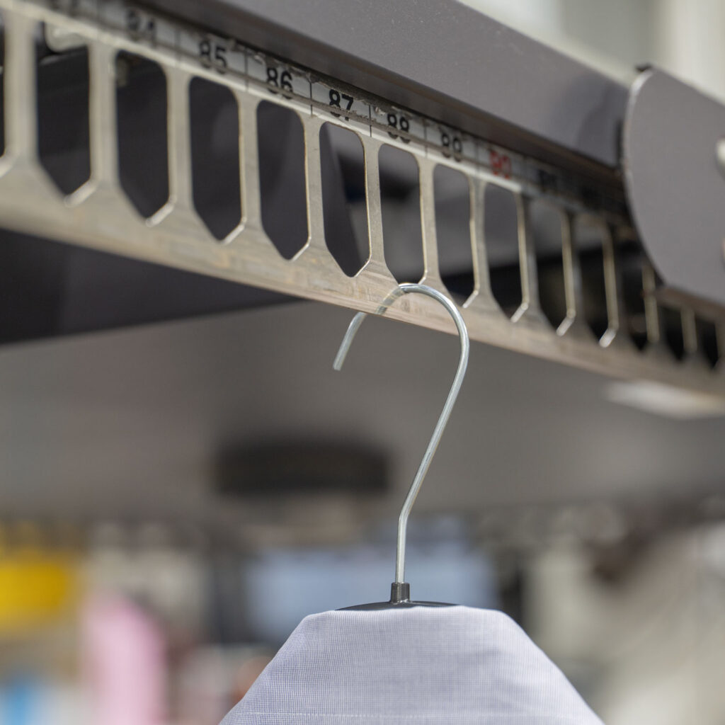 Close-up of a garment on an automated dry cleaning conveyor system inside a professional garment care facility